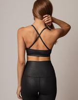 Person wearing a black sports bra and leggings against a neutral background