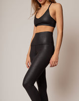 Person wearing a black sports bra and leggings set on a neutral background