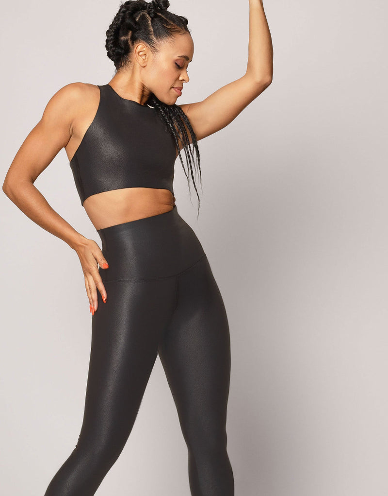 Woman wearing black athletic outfit on a plain background