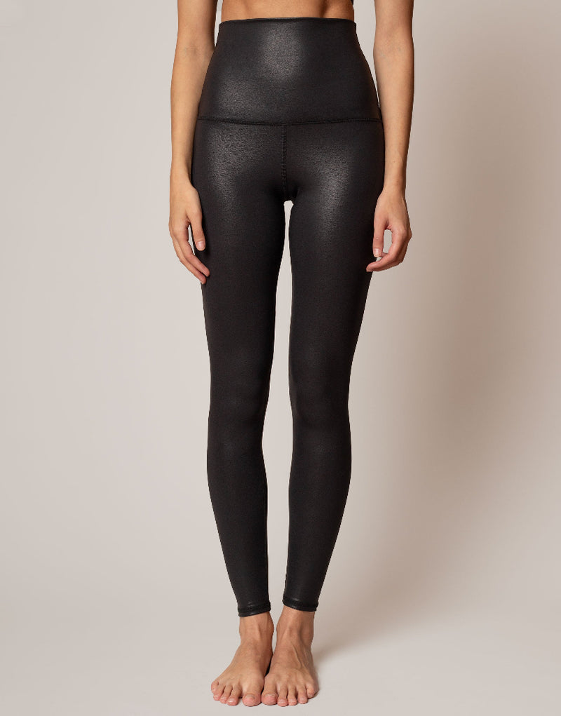 Person wearing black leggings on a beige background