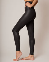 Person wearing black shiny leggings on a plain background
