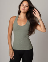 Woman wearing a green tank top and black leggings against a plain background