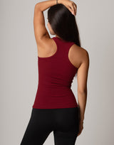 Person wearing a red tank top and black pants against a gray background