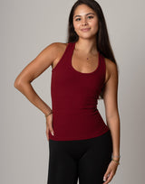 Woman wearing a red tank top and black pants against a gray background