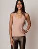 Woman wearing a beige tank top and black leggings against a plain background