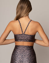 Person wearing a leopard print sports bra and leggings on a neutral background