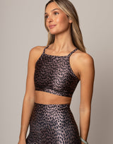 Woman wearing a leopard print sports bra and leggings on a neutral background