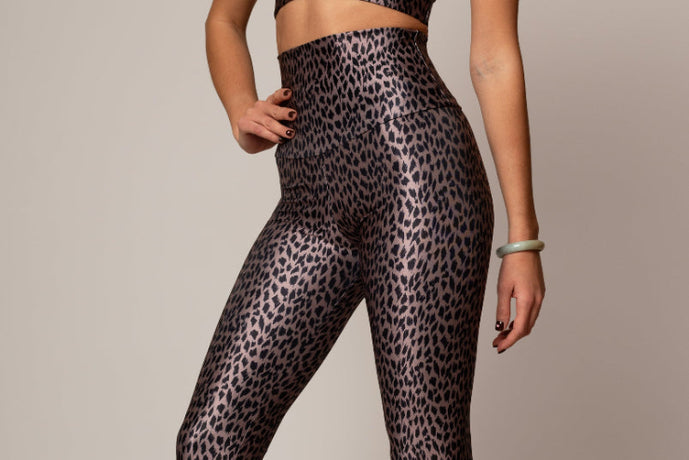 Person wearing leopard print leggings on a plain background