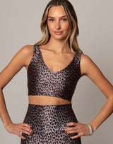 Woman wearing a leopard print sports bra and leggings on a gray background