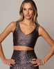 Woman wearing a leopard print sports bra and leggings on a gray background