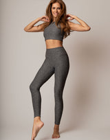 Woman wearing a gray athletic outfit on a plain background