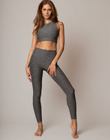 Woman wearing a gray athletic outfit on a plain background