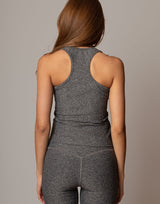 Person wearing a gray tank top and leggings set against a neutral background