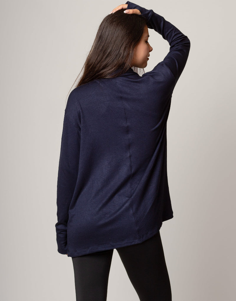 Woman wearing a navy blue cardigan over a red top on a gray background