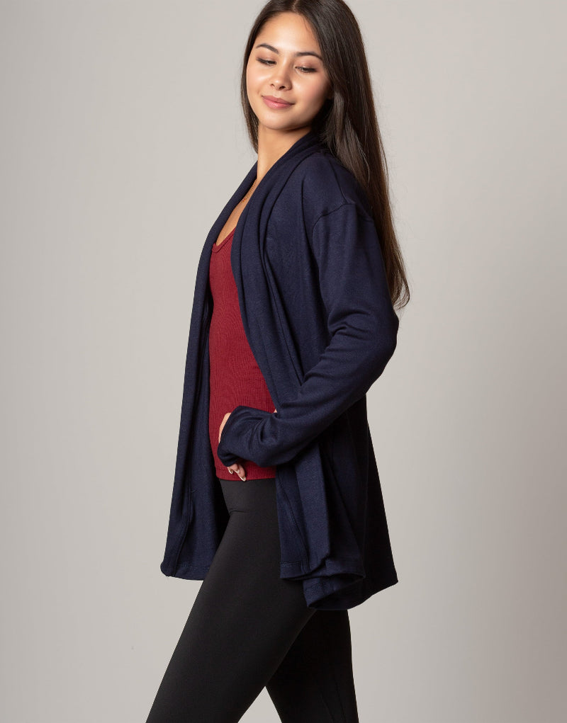 Woman wearing a navy blue cardigan over a red top on a gray background