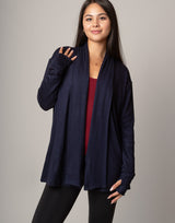 Woman wearing a navy blue cardigan over a red top on a gray background