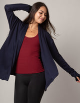 Woman wearing a navy blue cardigan over a red top on a gray background