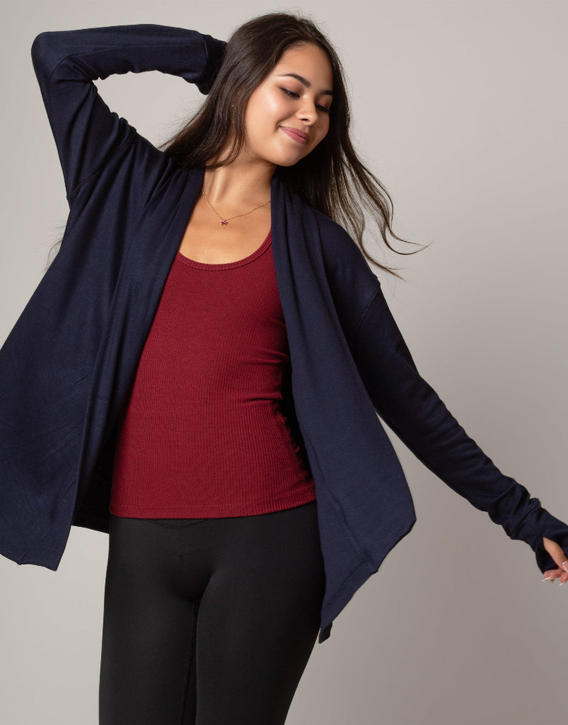 Woman wearing a navy blue cardigan over a red top on a gray background