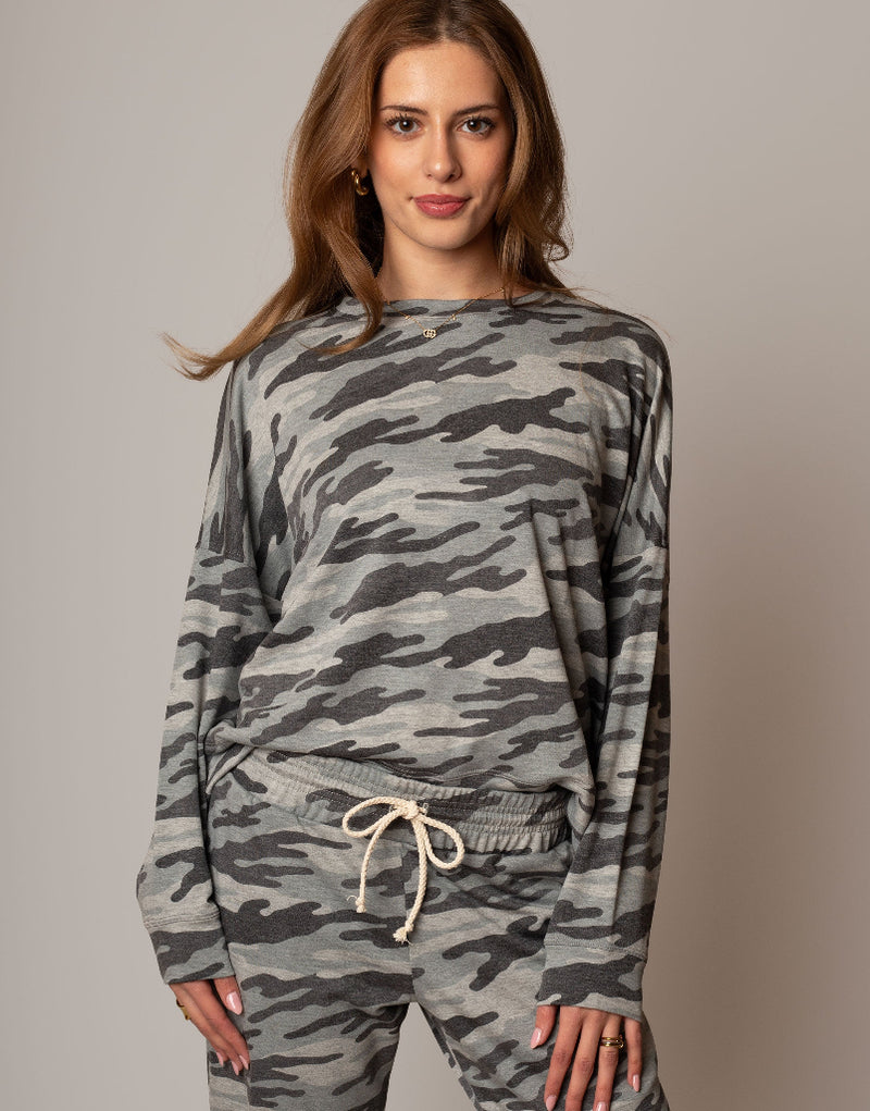 Woman wearing a camouflage outfit against a plain background