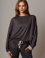 Woman wearing a dark gray long-sleeve top and pants on a gray background