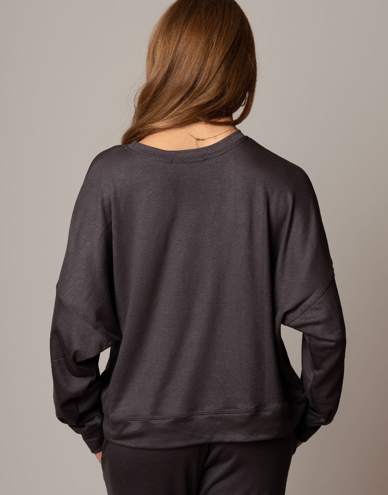 Person wearing a dark gray sweatshirt against a plain background