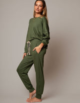 Woman wearing a green lounge set against a plain background