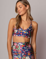 Woman wearing a colorful floral sports bra and leggings on a gray background